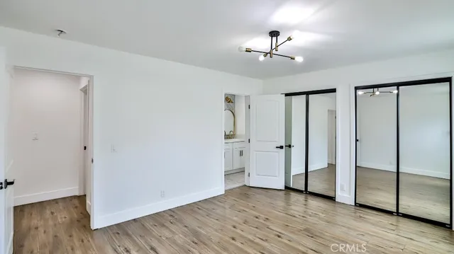 an empty room with wooden floor cabinet and windows