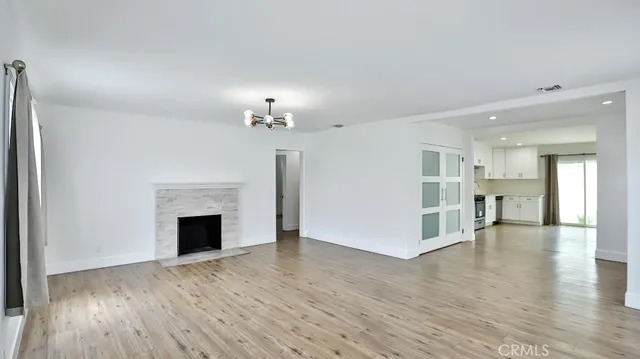 a view of an empty room with wooden floor and a fireplace
