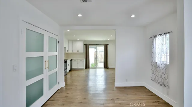 a view of a hallway with wooden floor and a kitchen