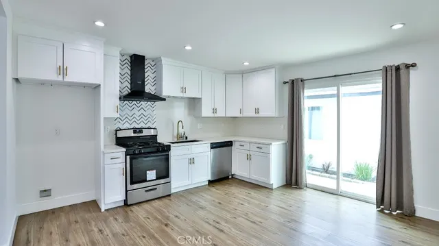 a kitchen with stainless steel appliances granite countertop a stove a sink and a refrigerator with wooden floor