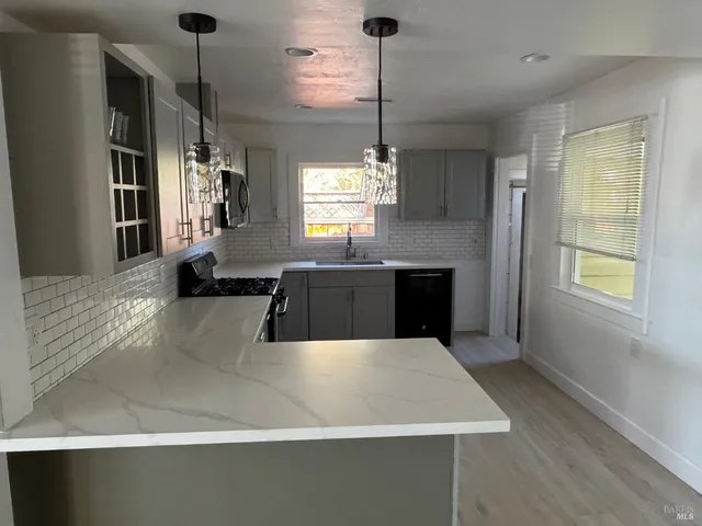 a large kitchen with kitchen island a large counter top space a sink stainless steel appliances and cabinets