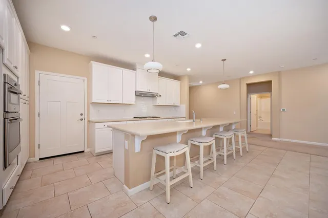 a large kitchen with kitchen island granite countertop a table and chairs in it