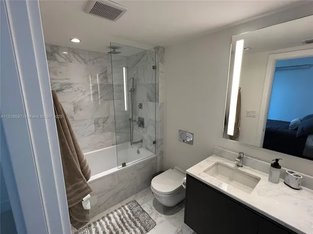 a bathroom with a sink a toilet a mirror and shower