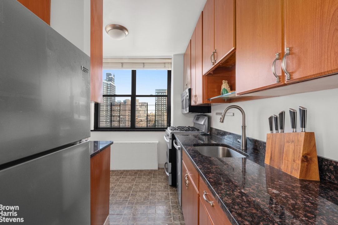 301 East 87th Street, Unit 25D Manhattan, NY 10128 - Photo 4 of 10 a kitchen with granite countertop a sink a stove and cabinets