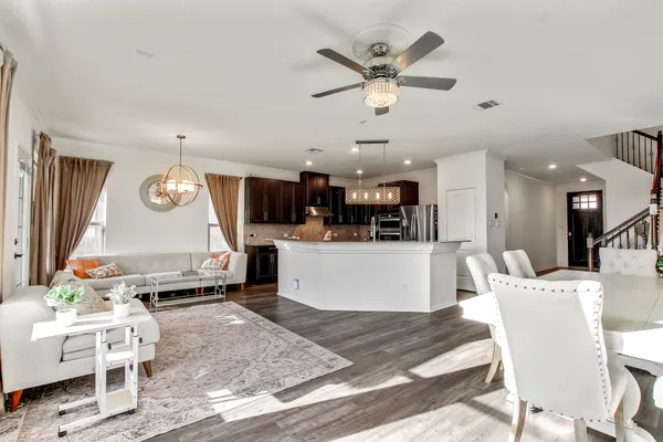 a living room with couches kitchen view and a dining table with kitchen view