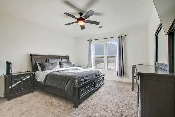 a spacious bedroom with a bed a dresser and a large window