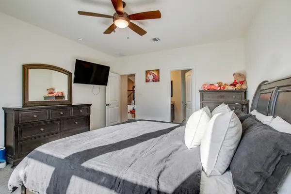 a bedroom with a bed a dresser and a flat screen tv