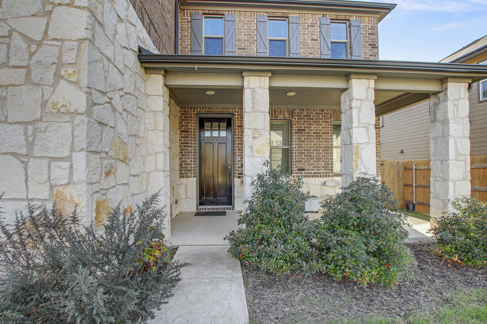205 Travers Stake Trail Elgin, TX 78621 - Photo 3 of 28 View of exterior entry with brick siding, covered porch, and stone siding