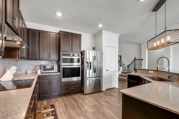 a kitchen with stainless steel appliances a sink a stove a refrigerator cabinets and wooden floor