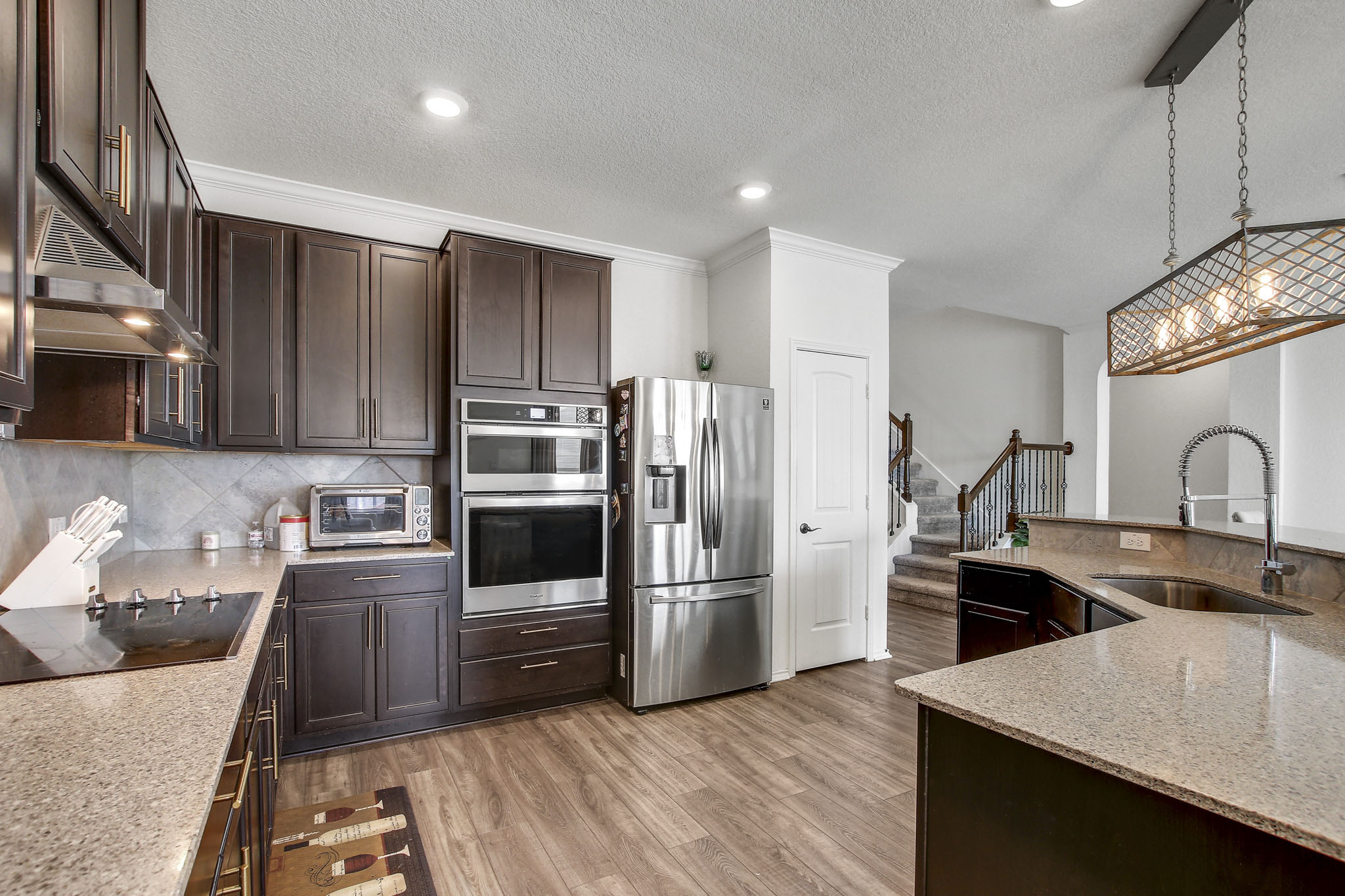 205 Travers Stake Trail Elgin, TX 78621 - Photo 8 of 28 Kitchen featuring stainless steel appliances, light stone countertops, decorative light fixtures, dark wood finish cabinetry, and dark wood-style flooring