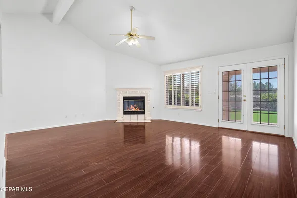an empty room with wooden floor fan and windows