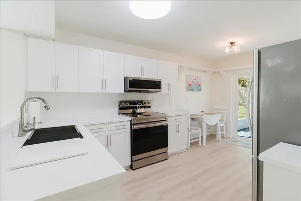 a kitchen with stainless steel appliances a stove a sink a microwave and a refrigerator