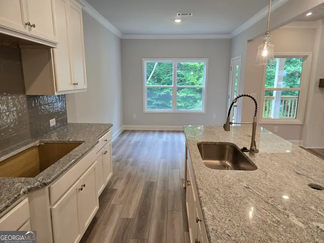 a kitchen with granite countertop a sink wooden floor and a large window