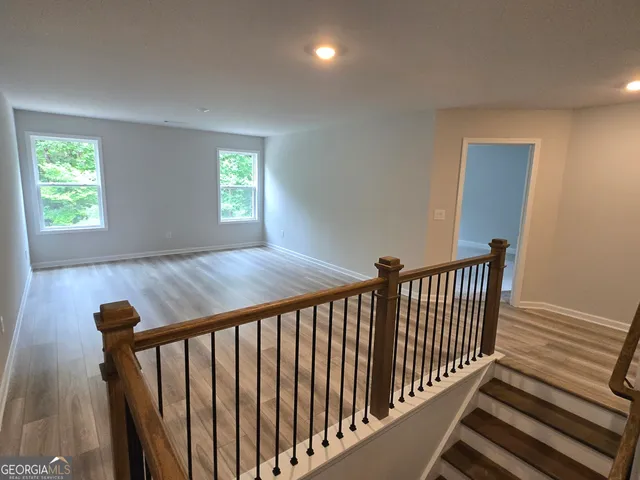 a view of a hallway with wooden floor and stairs