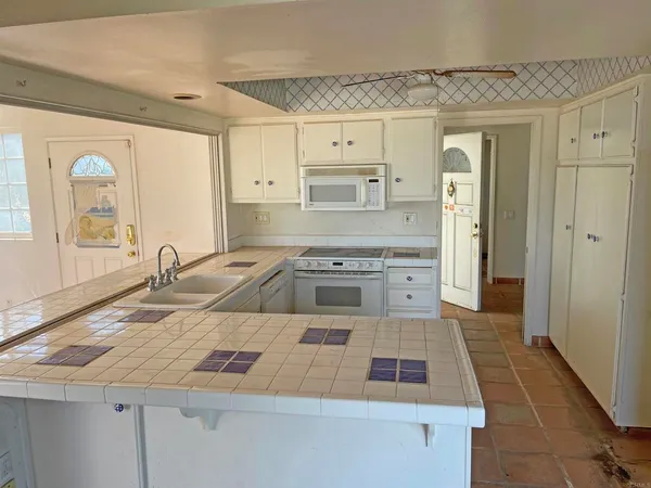 a kitchen with granite countertop white cabinets and white appliances