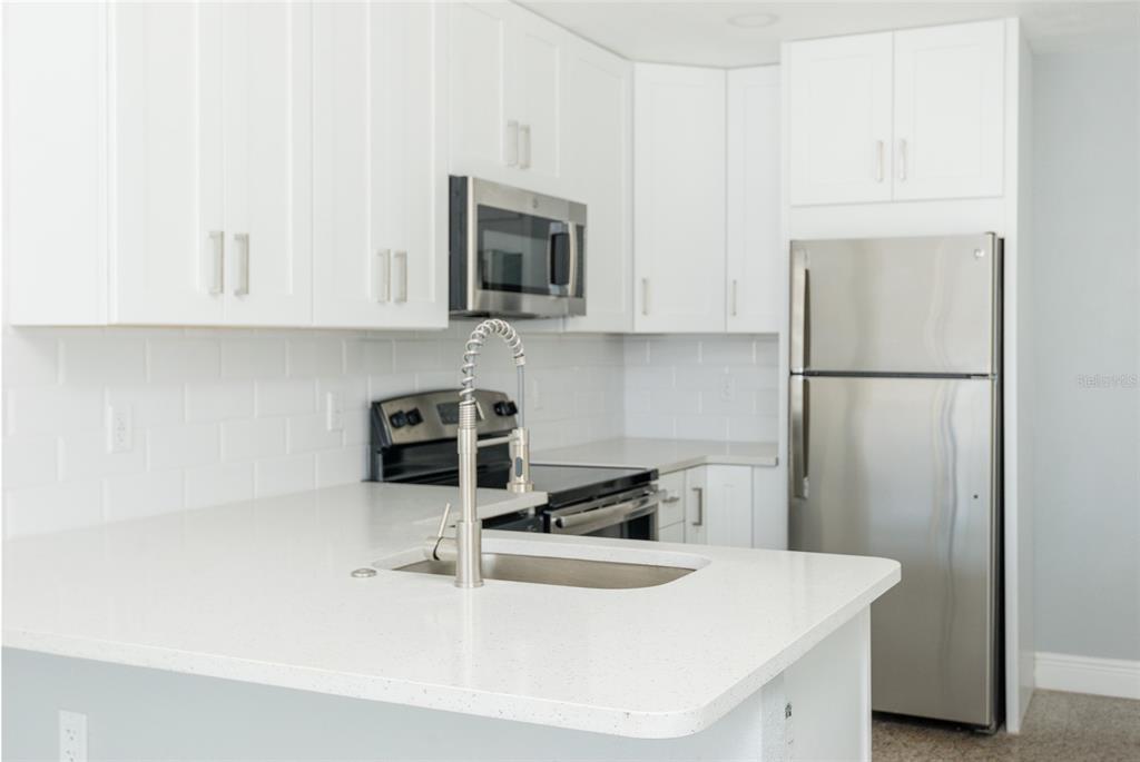 13248 4th Street East Madeira Beach, FL 33708 - Photo 22 of 47 a kitchen with stainless steel appliances granite countertop a sink a refrigerator a microwave and cabinets