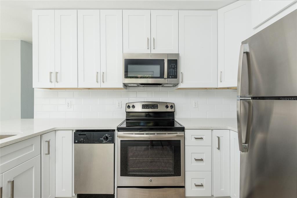 13248 4th Street East Madeira Beach, FL 33708 - Photo 24 of 47 a kitchen with stainless steel appliances granite countertop white cabinets a refrigerator and a stove with a refrigerator