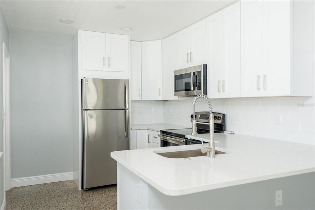 13248 4th Street East Madeira Beach, FL 33708 - Photo 10 of 47 a kitchen with stainless steel appliances granite countertop a refrigerator a stove a sink and white cabinets