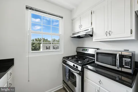 a kitchen with white cabinets and a stove top oven