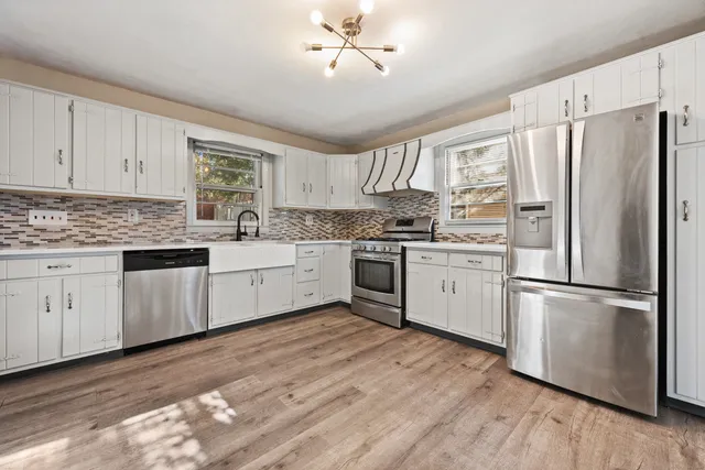 a kitchen with white cabinets white stainless steel appliances and sink