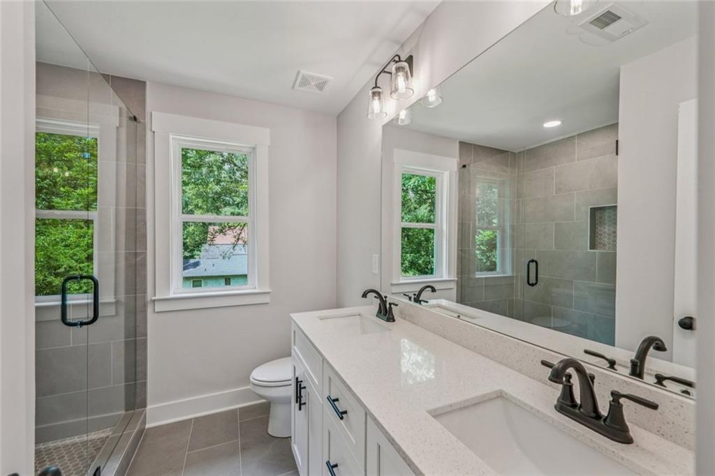 1179 Booker Avenue Southwest Atlanta, GA 30310 - Photo 38 of 54 a bathroom with a granite countertop sink a toilet and a large mirror