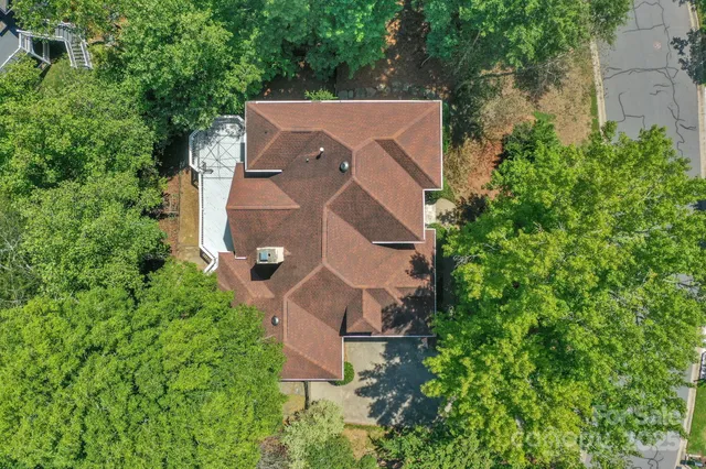 an aerial view of a house with a yard and trees all around