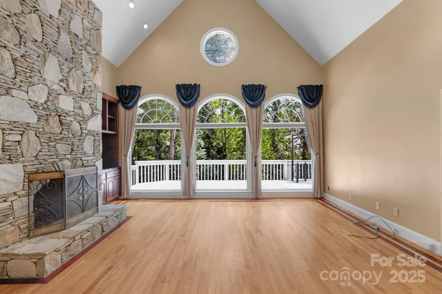 a view of an empty room with wooden floor and a large window