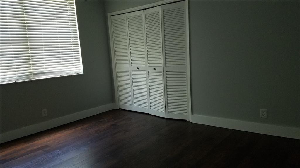3100 North Course Lane, Unit 210 Pompano Beach, FL 33069 - Photo 18 of 28 an empty room with wooden floor and a window