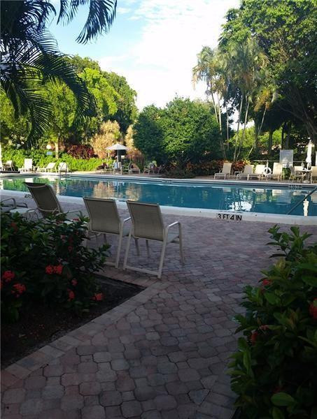 3100 North Course Lane, Unit 210 Pompano Beach, FL 33069 - Photo 27 of 28 a view of a lake with a bench and trees around