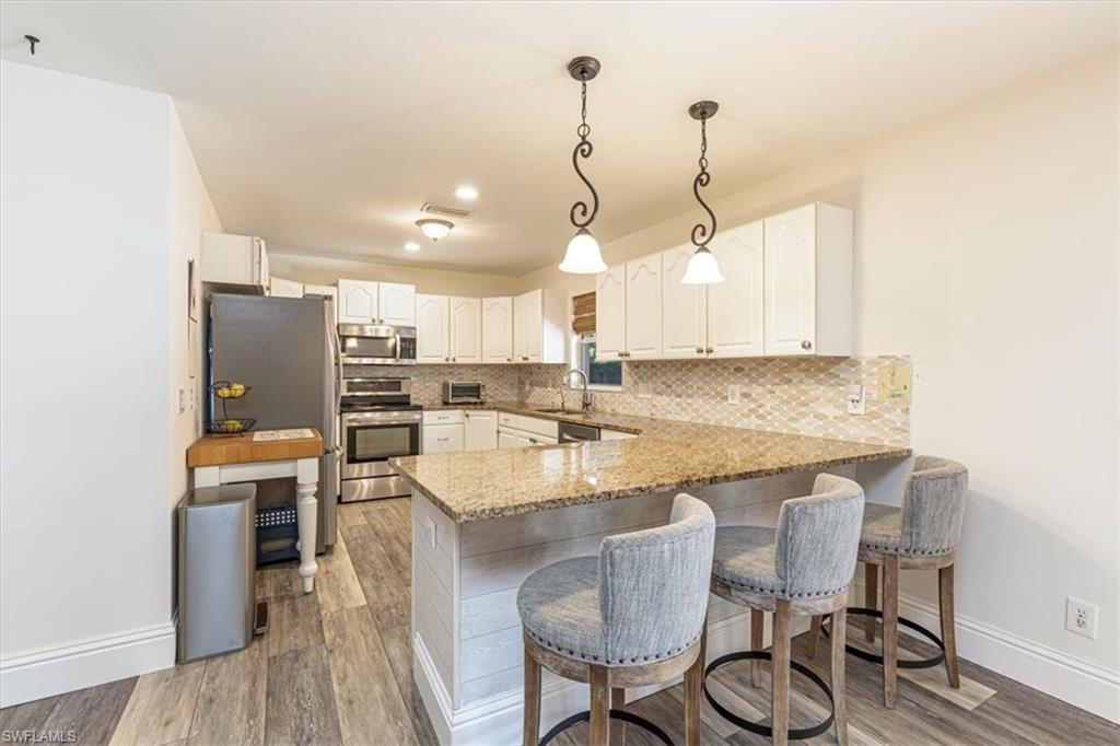 960 21st Street Southwest Naples, FL 34117 - Photo 7 of 33 a kitchen with a table chairs wooden floors and a view of living room