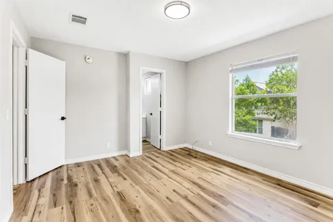 a view of a bedroom with wooden floor and a window