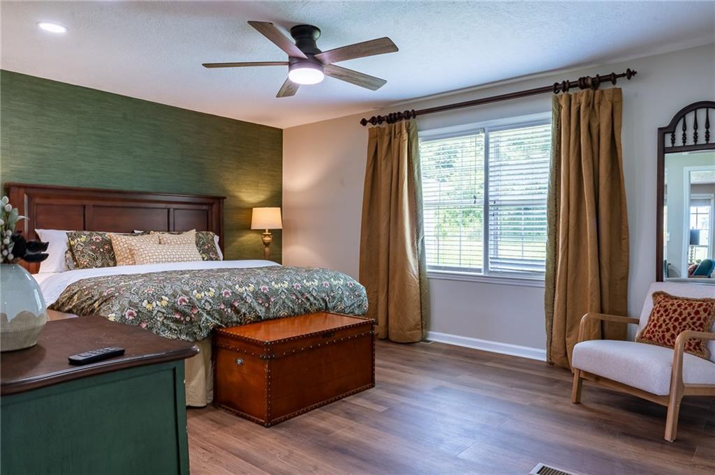 6938 Story Mill Road Hephzibah, GA 30815 - Photo 26 of 36 a bedroom with a large bed a chandelier and windows