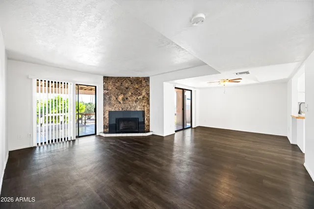 an empty room with wooden floor fireplace and windows