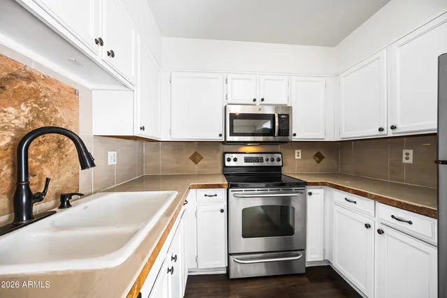 a kitchen with white cabinets a sink and stainless steel appliances