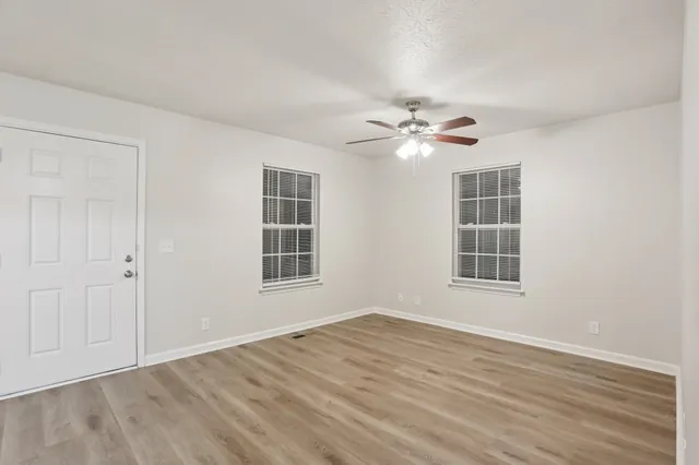 an empty room with wooden floor and windows