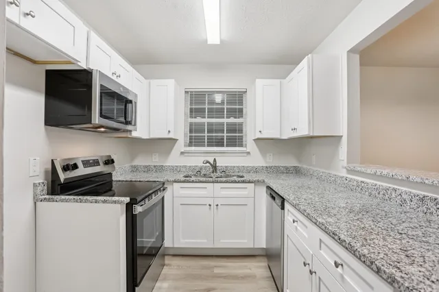 a kitchen with stainless steel appliances granite countertop a sink stove a microwave and cabinets