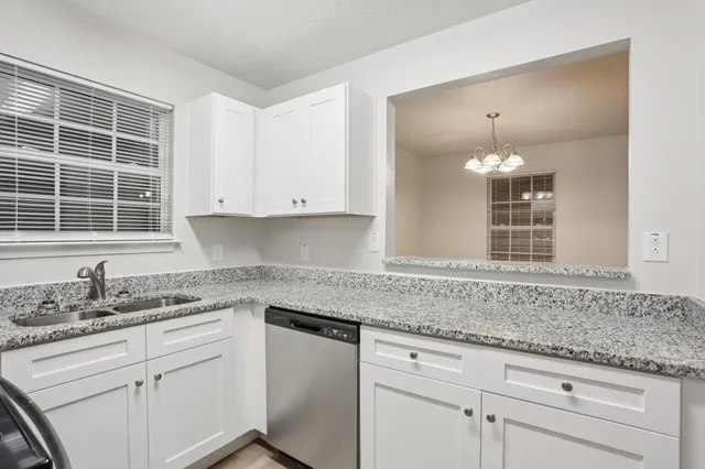 a kitchen with granite countertop white cabinets and a sink