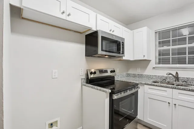 a kitchen with stainless steel appliances granite countertop white cabinets a microwave oven a sink and dishwasher