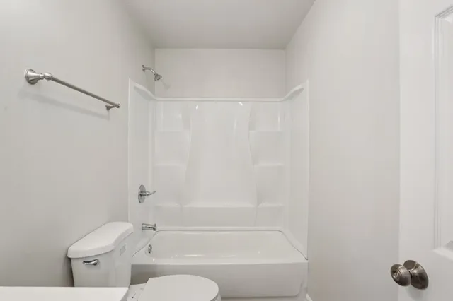 a bathroom with a granite countertop bathtub shower sink vanity and toilet