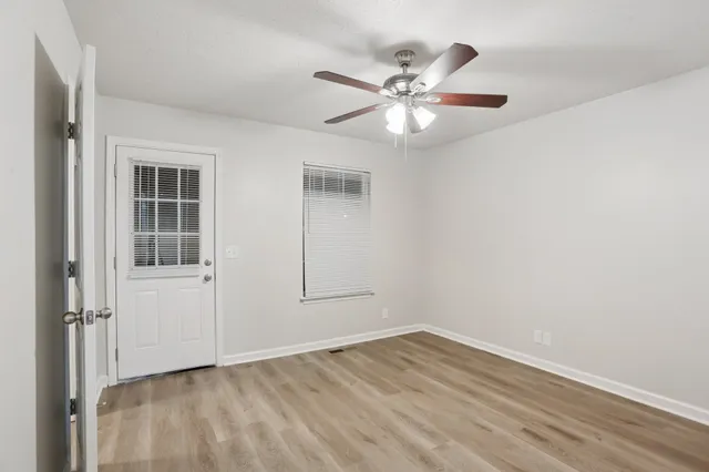 an empty room with wooden floor closet and windows