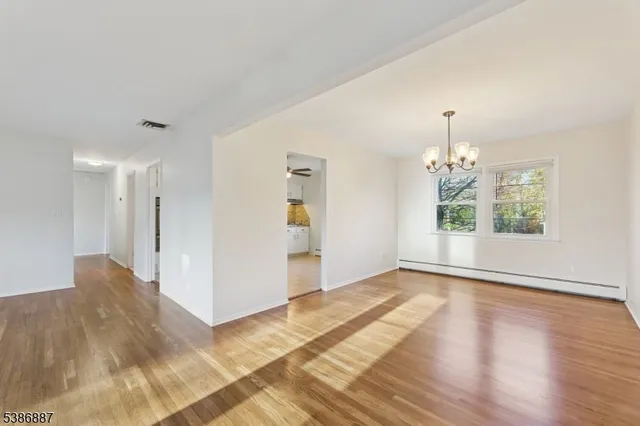 a view of an empty room with window and wooden floor