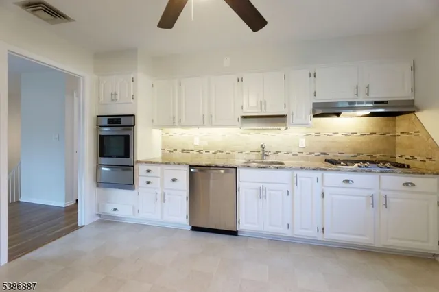 a kitchen with granite countertop white cabinets and stainless steel appliances