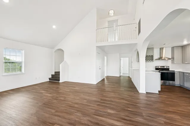 a view of empty room with wooden floor and kitchen