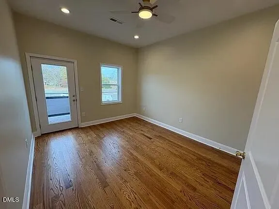 an empty room with wooden floor and windows