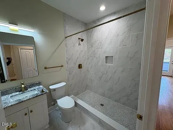a bathroom with a granite countertop sink a toilet and shower