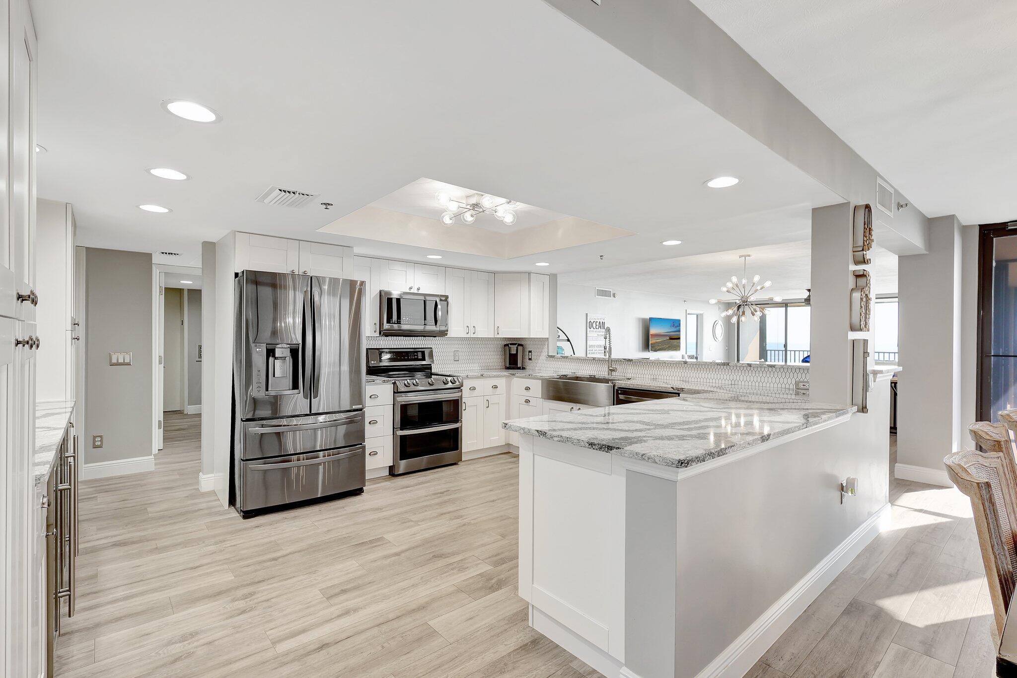 4000 North Hwy A1A, Unit 402 Hutchinson Island, FL 34949 - Photo 14 of 60 a kitchen with stainless steel appliances kitchen island granite countertop a stove and a refrigerator