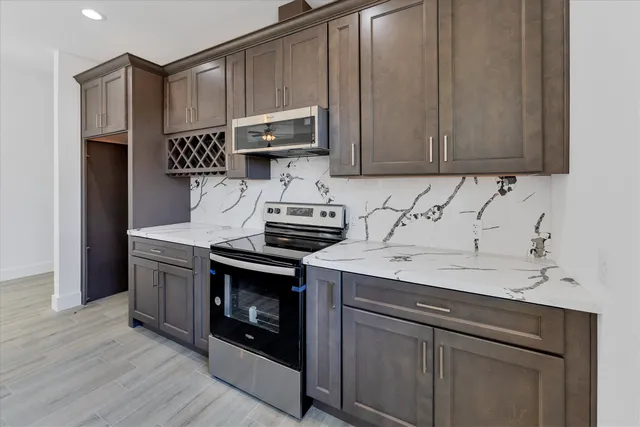 a kitchen with stainless steel appliances granite countertop a stove a sink and a microwave