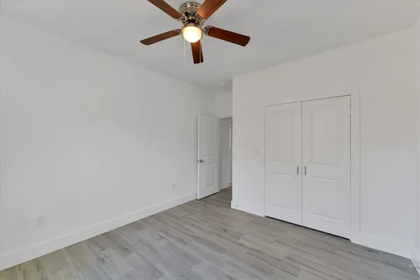 an empty room with wooden floor a ceiling fan and closet