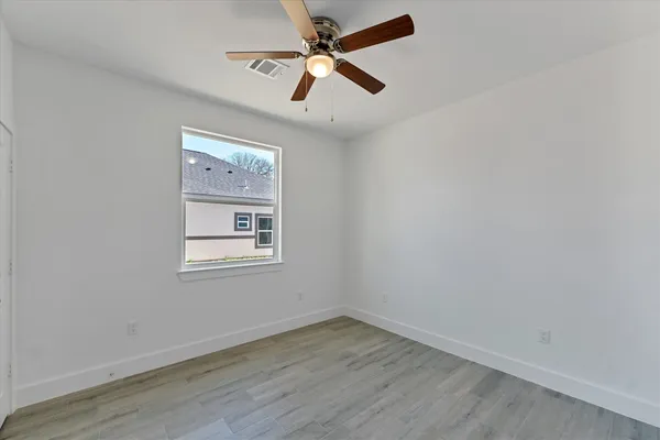 an empty room with a window and a fan