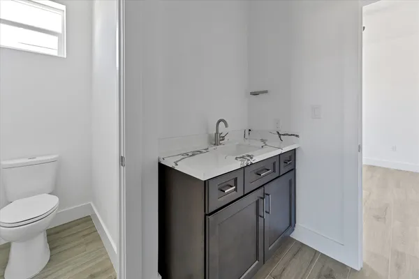 a utility room with sink toilet and wooden floor